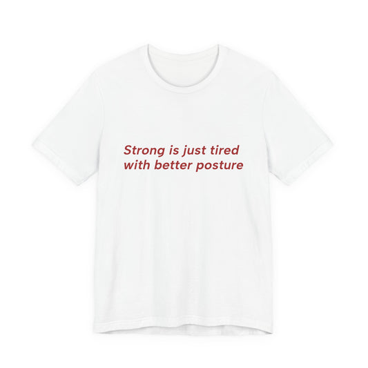 A white short-sleeve crewneck t-shirt with the text 'Strong is just tired with better posture' printed in red across the chest, displayed on a clean white background.