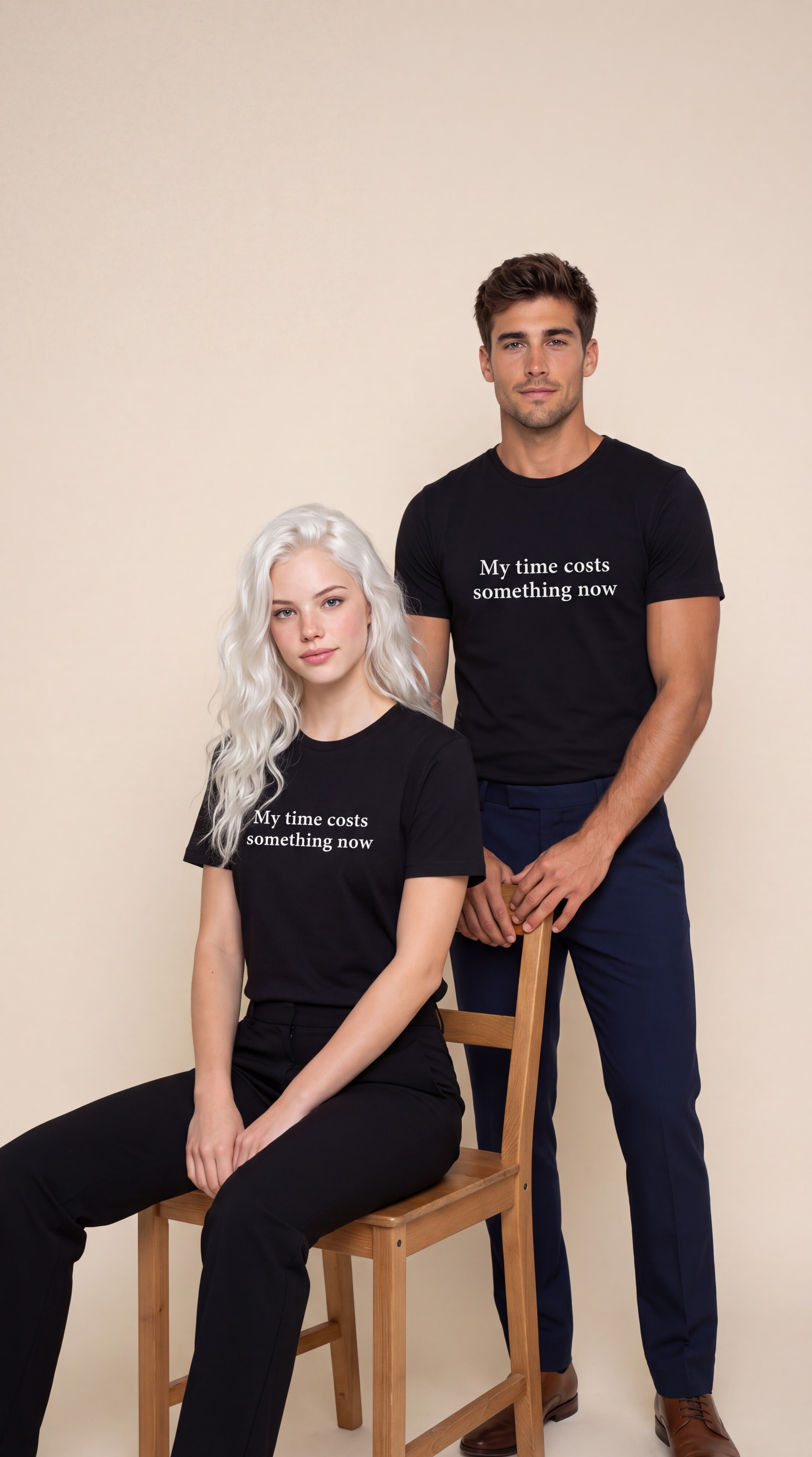 A man and a woman modeling matching black graphic t-shirts with the white printed text 'My time costs something now.' The woman sits on a wooden chair while the man stands behind her.